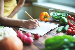 Woman writing meal plan in a journal