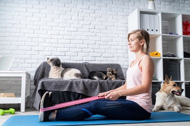 Woman doing fitness with rubber resistance band at home