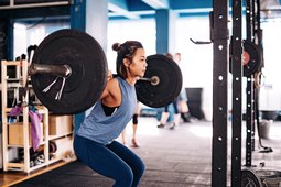 woman doing barbell squat for best lower-body workout