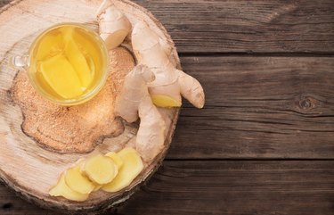 Glass cup of ginger tea with ginger root on wooden background, as an example of the best foods for sinus infection