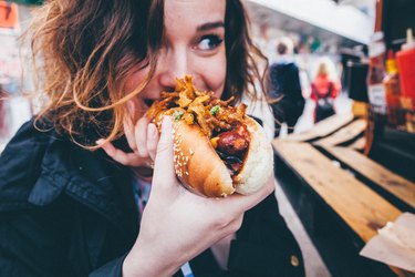 close-up of person eating a hot dog on the street